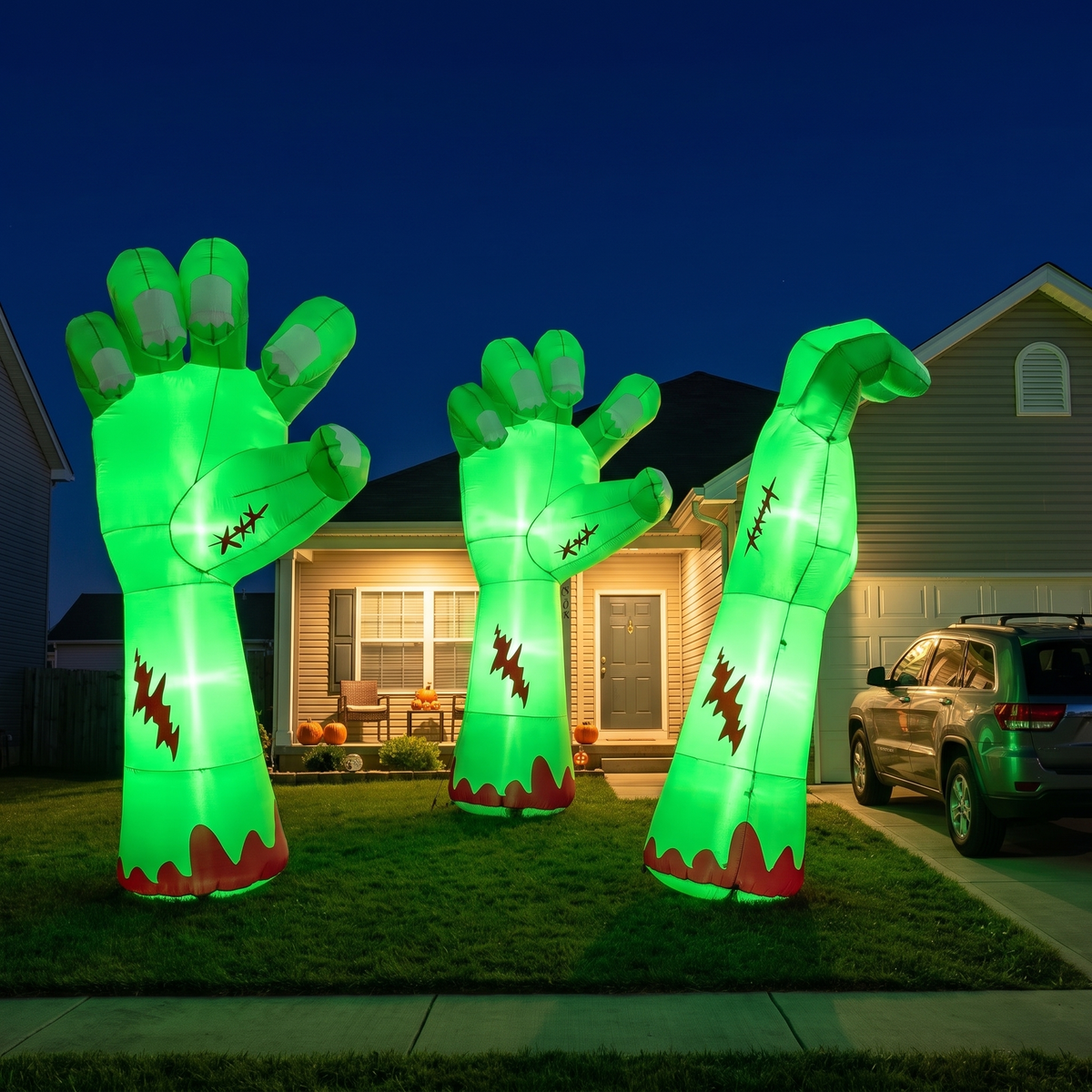 Three nine foot inflatable zombie arms glowing green across a suburban front yard at night